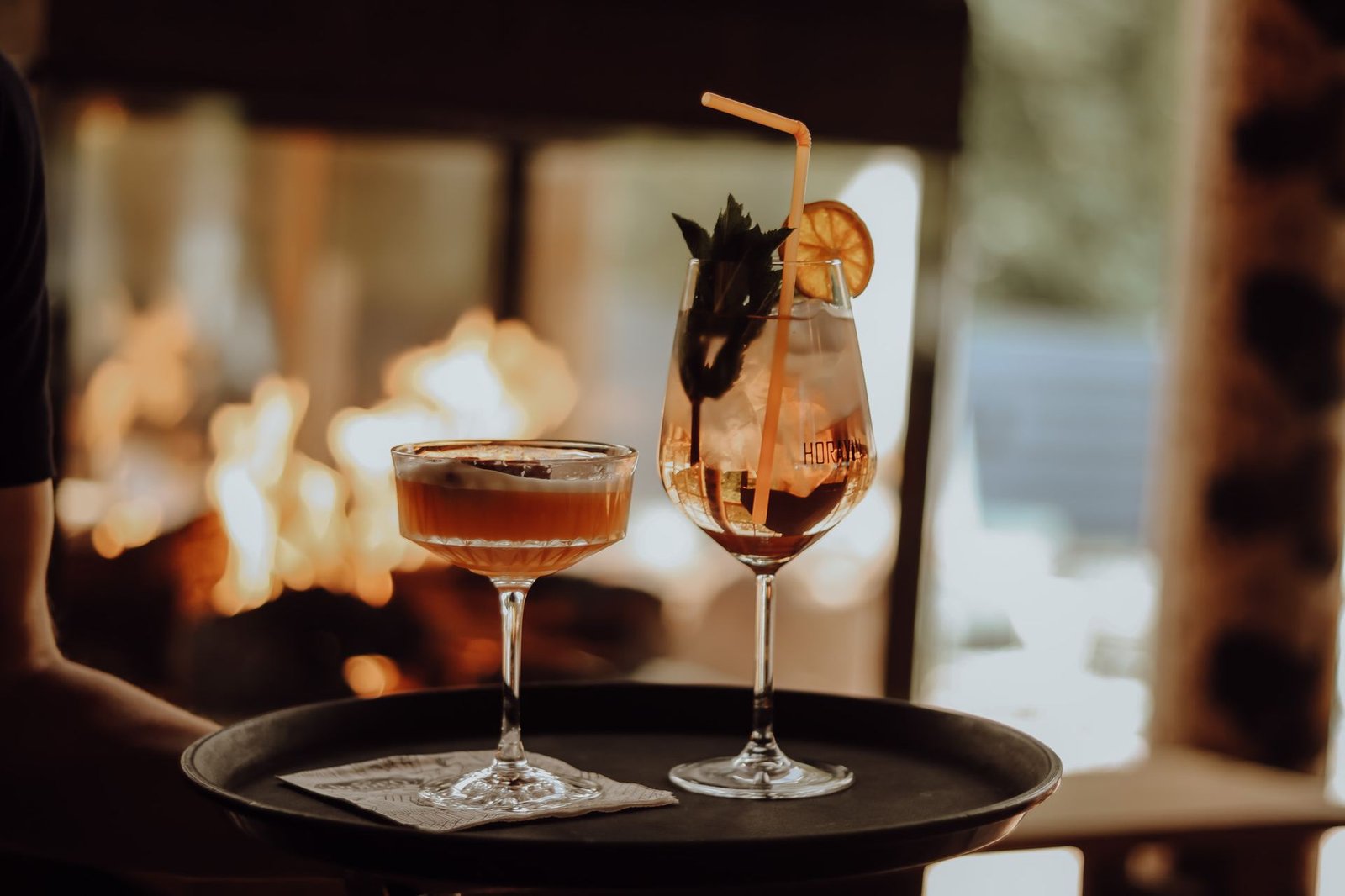 Twee cocktails op een dienblad bij het haardvuur