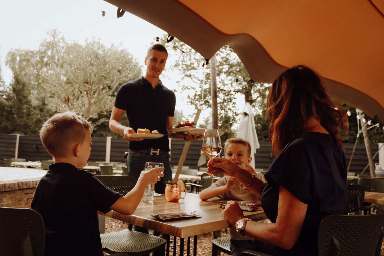Bediening serveert borden aan een familie op het terras